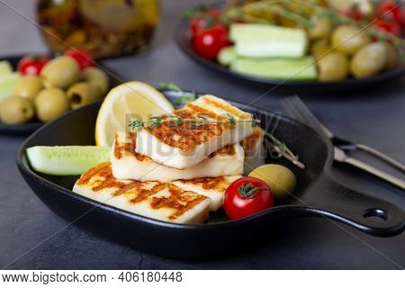 Grilled Haloumi Cheese On A Black Pan With Olives, Tomatoes, Cucumbers And Pepperoni. Close-up.