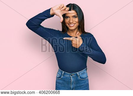 Young latin transsexual transgender woman wearing casual clothes smiling making frame with hands and fingers with happy face. creativity and photography concept. 