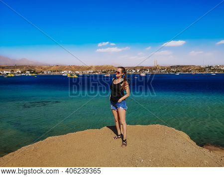 Young Pretty Woman Stands On A Rock Against The Background Of Sharm El-maya Bay In Sharm El Sheikh (
