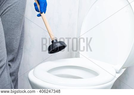 Cleaning Toilet Stuck With Suction Cup. Hands In Gloves Holding Ventuz In Toilet.