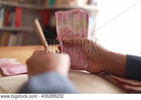 Close Up Of Woman Hand Counting Money Uang Indonesian Rupiah And Making Notes, Money Financial Manag