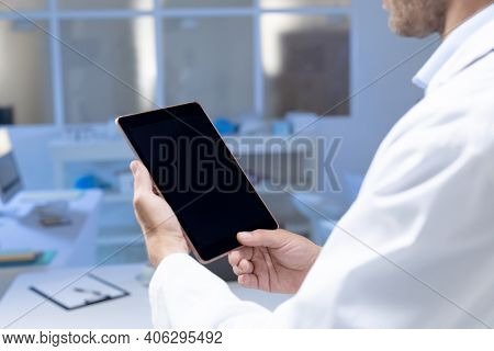 Midsection of caucasian male doctor making consultation video call using tablet. telemedicine online healthcare during quarantine lockdown.