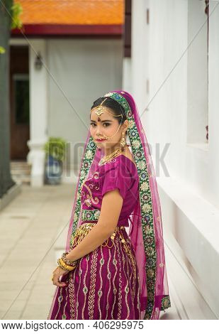 Portrait Asian Woman In A Margenta Indian Tradition Sari, She Is Looking At A Camera Next To The Whi