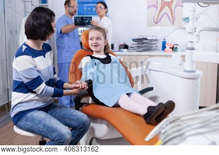 Little Girl With Missing Tooth Wearing Dental Bib Waiting For Examination In Dentist Office. Child W