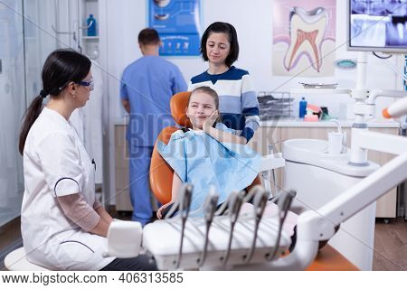 Little Girl With Painful Expression Showing Dentist Where Her Tooth Hurts During Dental Check Up. Ch