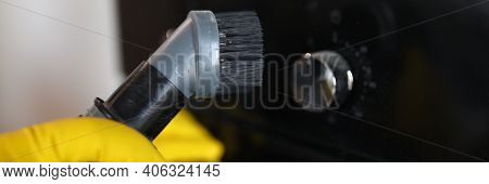 Close-up Of Persons Hand Cleaning Cookstove Display With Nozzle Of Grey Vacuum Cleaner. Male In Prot