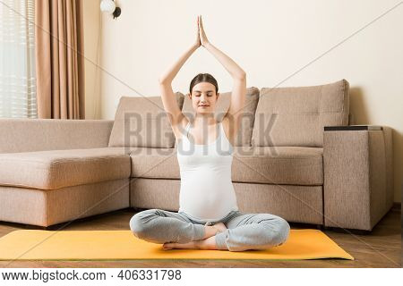 Beautiful Young Pregnant Woman Sitting On Mat In Yoga Pose At The Home. Pregnancy Yoga And Fitness C