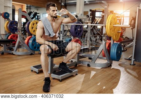 Attractive Athletic Young Man Bodybuilder Fitness Model Drink Water After Exercise With Barbell On T