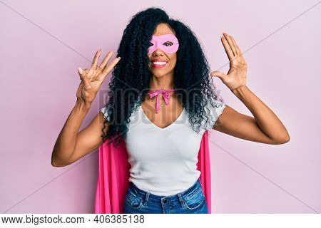 Middle age african american woman wearing super hero costume showing and pointing up with fingers number eight while smiling confident and happy. 