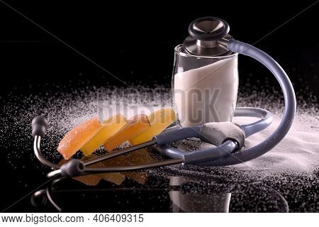 Stop Diabetes Concept. Glass Of Sugar With Stethoscope And Sweets On Dark Background. Danger Of Suga