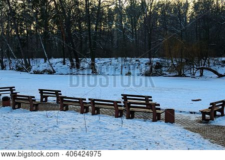 Picturesque View Of Resting Area With Wooden Empty Benches At The Lake Shore. Scenic Winter Landscap