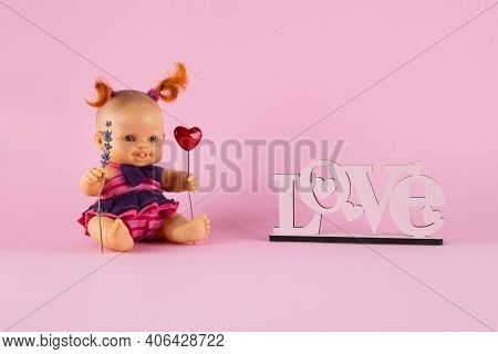 Freckled White Doll Girl With Two Curly Red Tails Holds A Heart And A Sprig Of Lavender On A Pink Ba