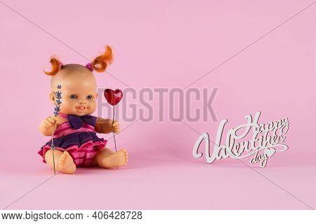 Freckled White Doll Girl With Two Curly Red Tails Holds A Heart And A Sprig Of Lavender On A Pink Ba