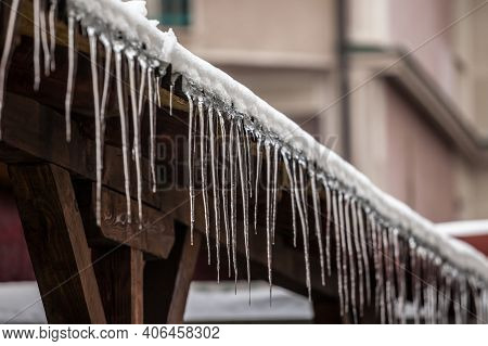 Icicles Forming Ice Stalactites Falling Fron The Edge Of The Eaves Of Gutters And Roofs Of A Residen