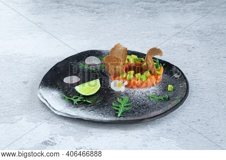 Portion Of Fresh Salmon And Avocado Tartar On Black Plate