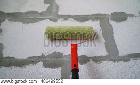 Roller And Foam Block. A Construction Roller With A Fur Nozzle On The Background Of A Wall Made Of A