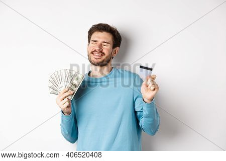 Cheerful Guy Celebrating Salary, Dancing With Plastic Credit Card And Money, Smiling Satisfied, Stan