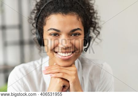 Headshot Of Friendly African American Millennial Woman In A Headset Sitting With Her Hands On A Chin