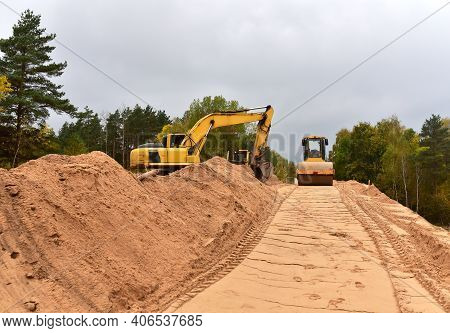 Excavator And Vibro Roller Soil Compactor At Road Construction And Bridge Projects In Forest Area. H