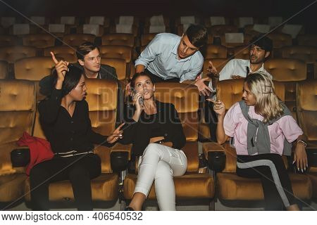 Young Woman Talking On The Phone Among Moviegoers So Annoying Others That Men And Others Who Sit Nex