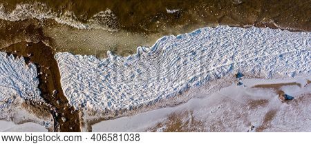 Aerial view over partialy frozen sea with white ice texture