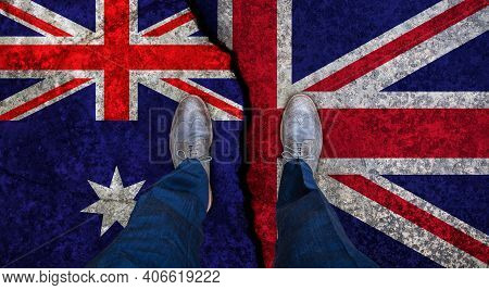 Business Man Stands On Cracked Flag Of Uk And Austrtalia. Political Concept