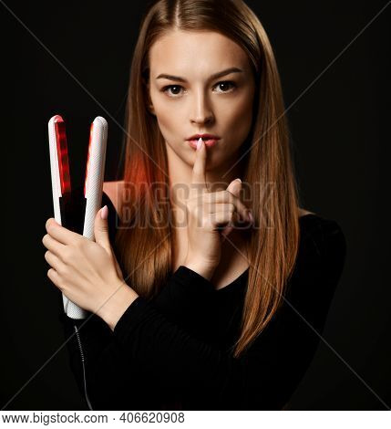 Young Pretty Woman Model Holds Modern Hair Straightener In Hand And Shows Gestures Silence Sign With