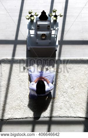 Man Buddhist In White Dress Sitting And Doing Meditation In Front Of Set Of Altar Table With Buddha 