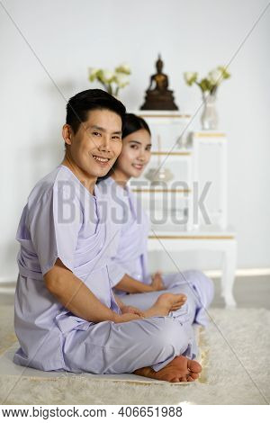 Man And Woman Buddhist In White Dress Sitting And Doing Meditation In Front Of Set Of Altar Table Wi