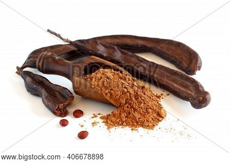 Dry Carob Powder In A Scoop And Pods Close Up Isolated On White