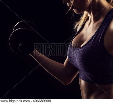 Slim Athletic Woman Holding Dumbbell In The Hand On Black
