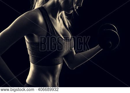 Slim Athletic Woman Holding Dumbbell In The Hand On Black