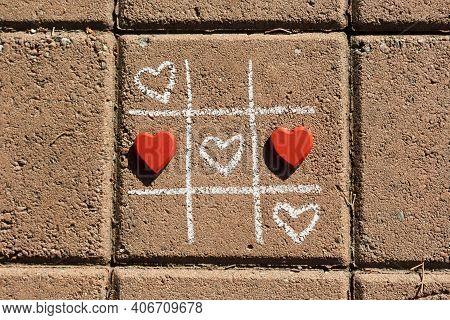 Chalk Tic-tac-toe Game With White And Red Hearts On Sidewalk In Sunlight