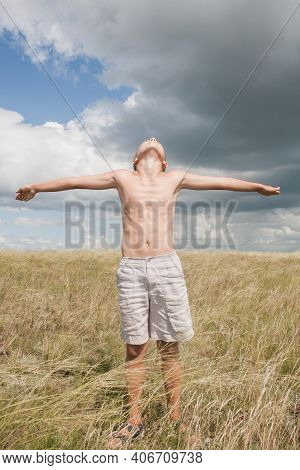 Boy In Shorts Stands In The Field. Boy Looks To The Sky. Dreamer Guy