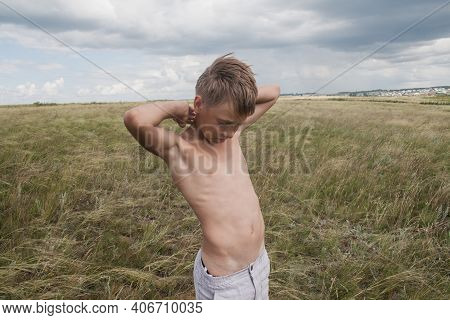 Boy In Shorts Stands In The Field. Boy Looks To The Sky. Dreamer Guy