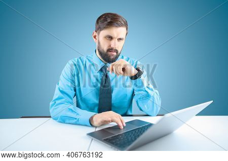 A Bearded Male Businessman Taps The Trackpad Behind His Laptop With His Finger