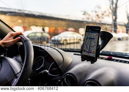 Using Waze Maps Application On Smartphone In Car Dashboard. Driver Using Maps App For Showing The Ri