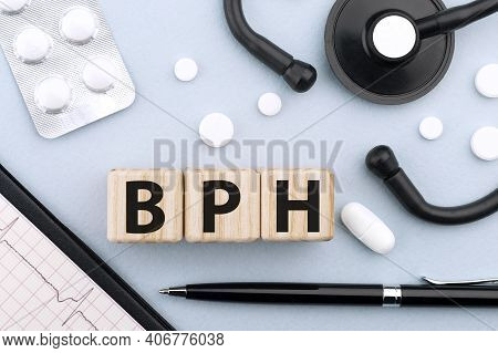 Word Bph On Wooden Cubes On Blue Background With Stethoscope, Pills, Capsules, Pen And Cardiogram. M