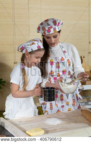 In The Kitchen, Mum Teaches Her Daughter How To Sift Wheat Flour For Pizza Dough. Family Learning In