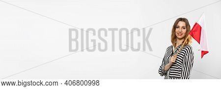 A Smiling Girl Holds One Polish National Flag In Her Hand. Isolated From The Background. A Shot In A