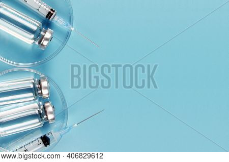 Vials Of Medicines And Syringes In A Petri Dish On A Blue Background. A Vaccine Against Covid-19.the