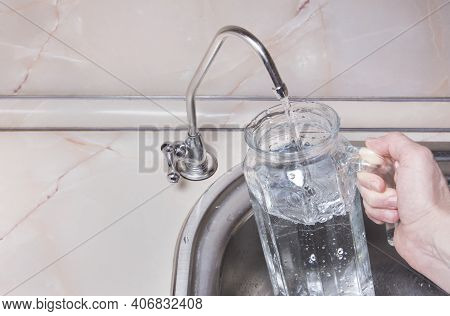 Pouring Filtered Water Into Glass Jug From Water Filter. Closeup Of Sink And Faucet. Drinkable Water