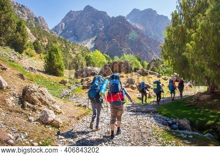Hikers With Backpacks Walking In Mountains. Group Of Friends In Fann Mountains, Tajikistan. Mountain