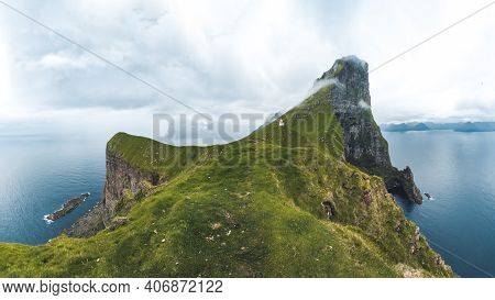 Kalsoy Island With Kallur Lighthouse On On Faroe Islands, Denmark, Europe. Clouds Over High Cliffs, 