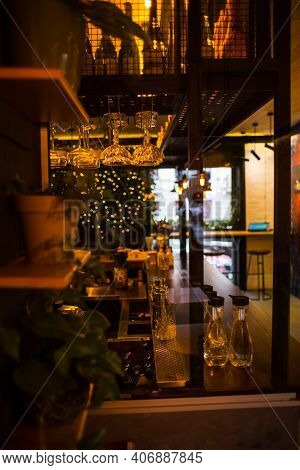 The Decor Of The Bar. Indoor Plants On Shelves Near The Bar Counter. Wine Glasses And Bottles With W