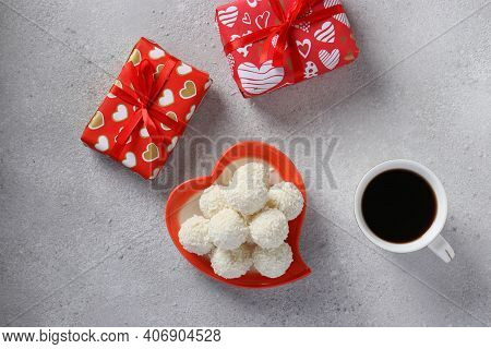 Sweet Coconut Rafaello Candies In A Heart-shaped Plate, Gifts And A Cup Of Coffee On A Light Backgro