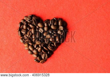 Roasted Coffee Beans On A Red Textured Background In The Form Of A Heart.