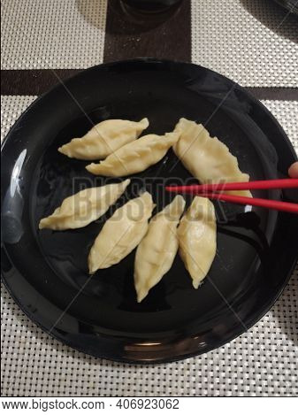 A Japanese Gedza Dumplings In A Plate Eating With Chopsticks In The Kitchen