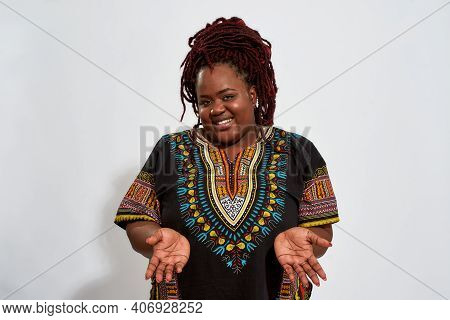 Embrassed Plump Young African American Woman Showing Open Arms In Front Of Her And Looking At Camera