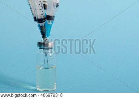 Close-up Of A Bottle Of Vaccine, And Five Medical Needles With Injections Stuck In The Bottle Cap On